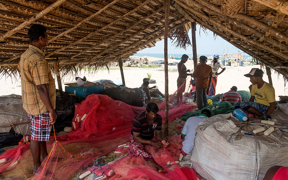 Fishermen repairing their nets on the beach